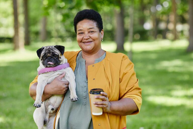 A woman holding a dog and a coffee cup